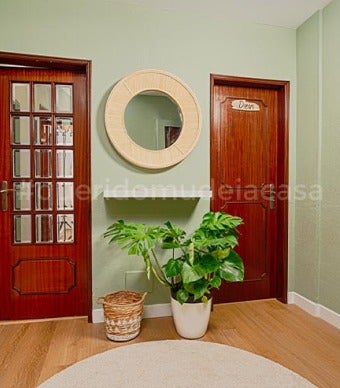 Hall de entrada com paredes verde seco, espelho de ráfia e prateleira por baixa, plantas em vasos para dar vida